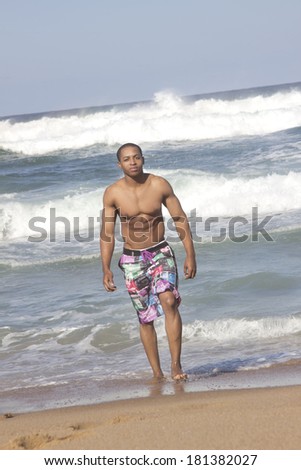 Young sexy African American Man walking out of the beach surf