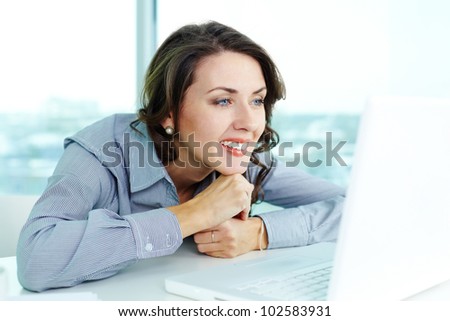 Smiling business woman looking at the screen of computer