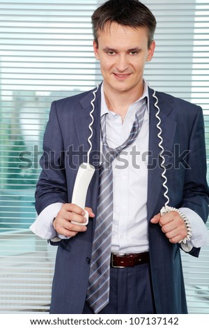 Sloppy businessman with phone receiver looking at camera