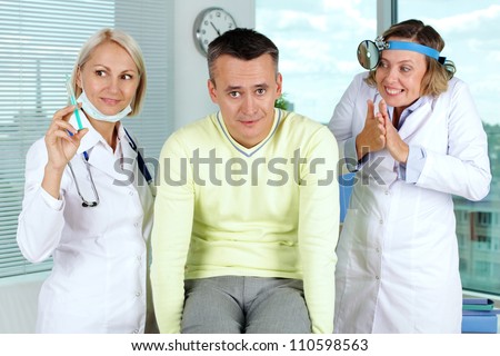 Portrait of two gloating female doctors giving first aid to male patient in hospital