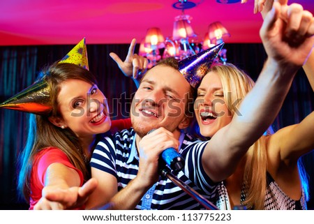 Portrait of happy people singing in microphone in the karaoke bar