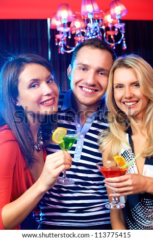 Portrait of happy friends with cocktails looking at camera at party