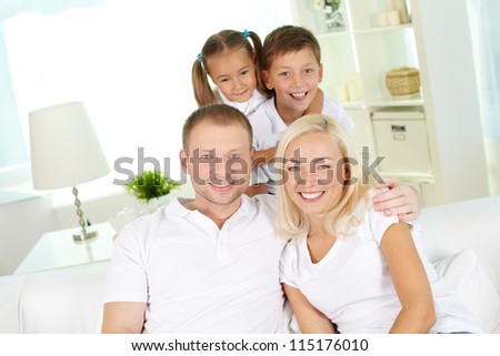Portrait of happy family with two children looking at camera at home