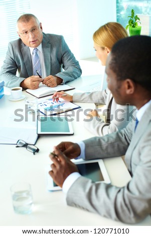 Portrait of confident senior boss looking at his employees at meeting