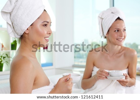 Girls in bath towels having tea in spa salon