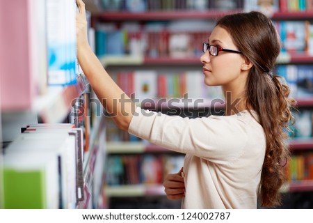 Portrait of serious girl in library looking for a book