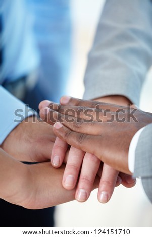 Vertical shot of a business group putting hands together to express their team spirit