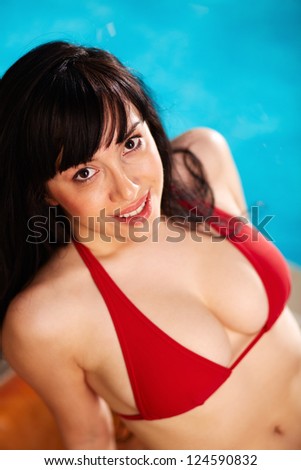 Portrait of lovely woman in bikini lying on mattress and looking at camera