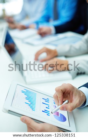 Image of human hand with pointer over business document in touchscreen at meeting