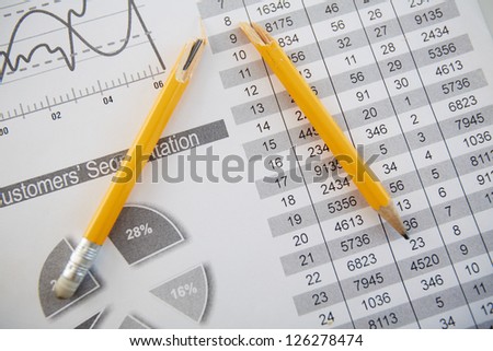 Close-up shot of a broken pencil lying over printed statistics