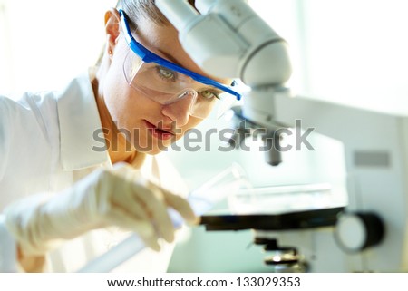 Female biochemist mixing substances to study under the microscope