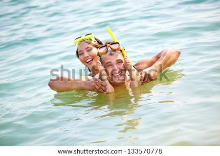 Hilarious couple having fun in water, guy holding his girlfriendÃ?Â¢??s feet by his face