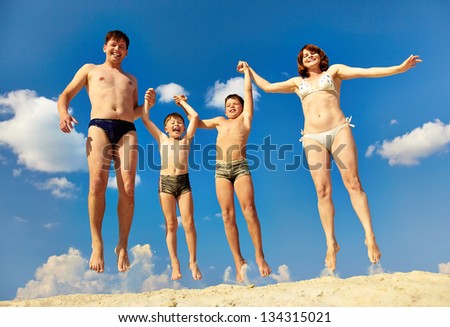 Photo of happy family jumping on sand during summer vacation