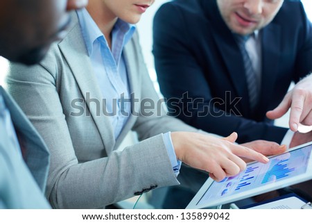 Image of female pointing at touchscreen during discussion of business document at meeting