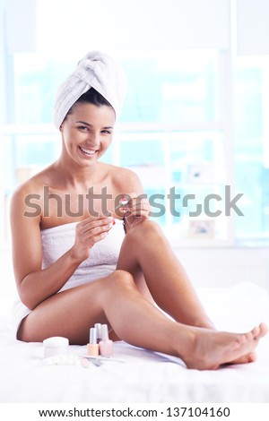 Girl with a towel on her head and body taking care of her fingernails
