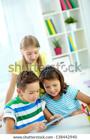 Portrait of happy classmates at workplace using digital tablet