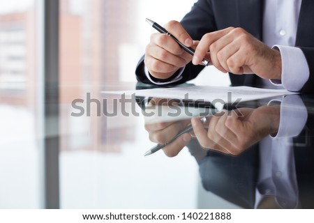 Close-up of male hands with pen over document