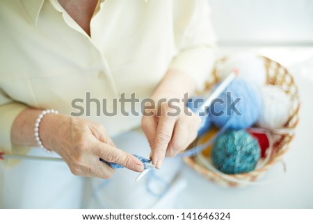 Hands of elderly woman knitting woolen clothes