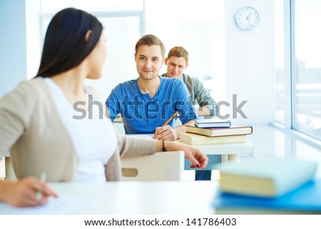 Portrait of smart student consulting his groupmate while carrying out test at lesson