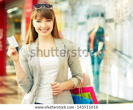 Pretty lady with shopping bags showing credit card