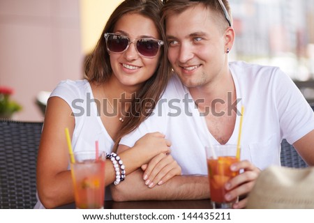 Young guy and his girlfriend sitting in cafe on summer day