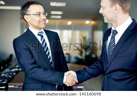 Portrait of elegant businessmen handshaking in conference hall