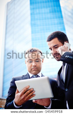 Vertical image of businessmen communicating via modern devices in the urban surroundings