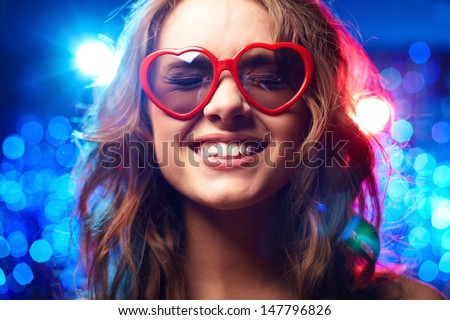 Girl with heart-shaped glasses and closed eyes smiling