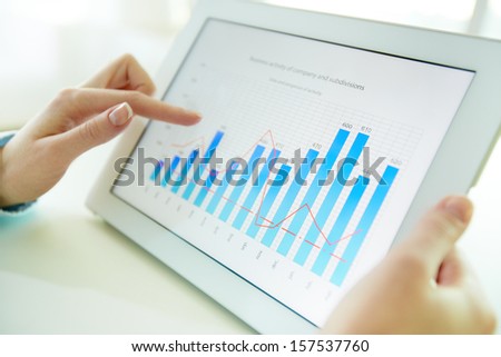 Female worker analyzing financial results with the help of a digital pad
