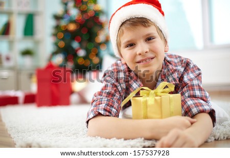 Portrait of cheerful boy with giftbox looking at camera on Christmas evening