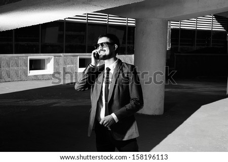 Black-and-white image of a smiling businessman speaking on the phone