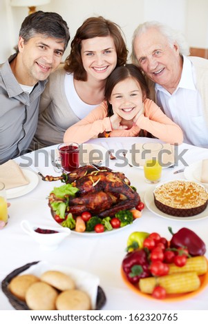 Portrait of happy family sitting at festive table and looking at camera