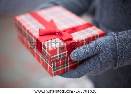 Image of gloved hand of guy holding box with Christmas present