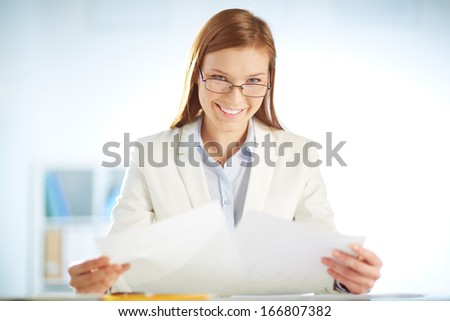 Young businesswoman sitting in office and working with papers