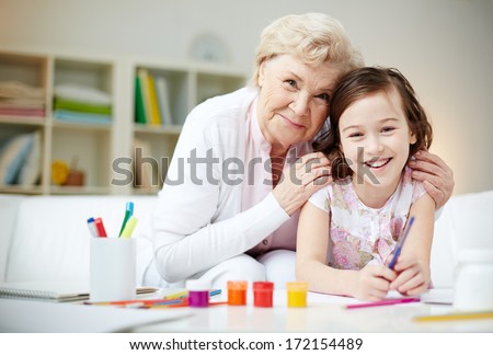 Portrait of happy girl and her grandmother looking at camera at home