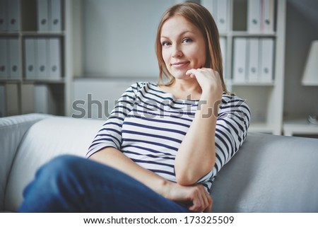 Calm woman in casual clothes looking at camera inside