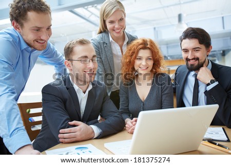 Group of business partners looking attentively at data in laptop at meeting