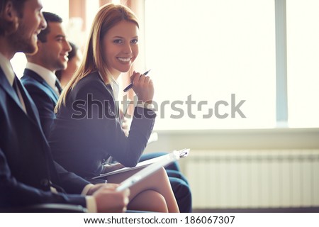 Row of business people sitting at seminar, focus on attentive young female