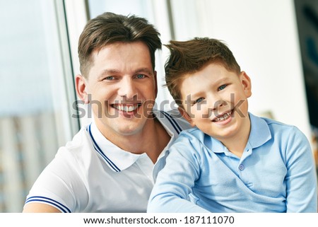 Photo of happy man embracing his son and both looking at camera
