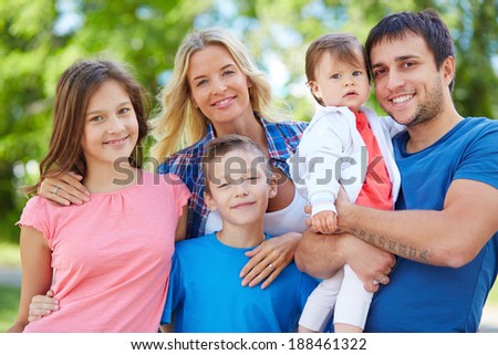 Photo of happy family looking at camera outdoors