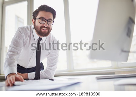 Happy businessman at workplace looking at camera in office