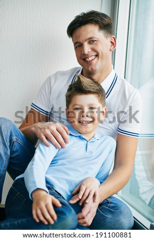 Photo of happy man and his son sitting by the window