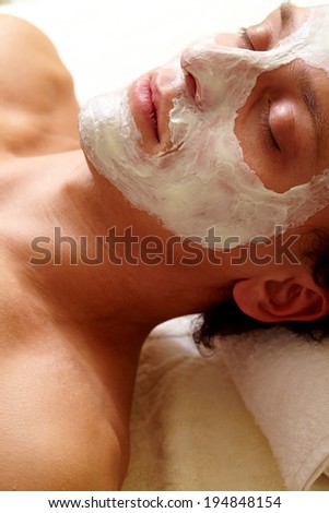 Young man having pore cleaning mask on his face