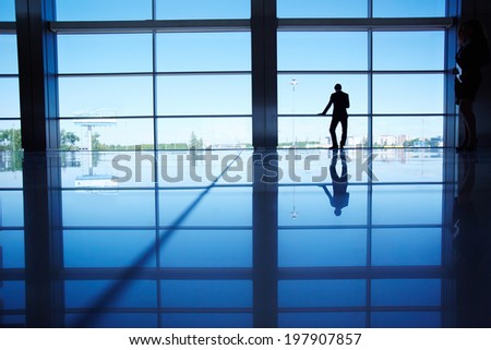 Outline of white collar worker standing by the window of office
