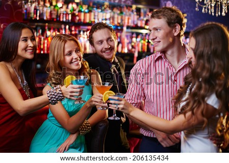Group of friends toasting with cocktails in the bar