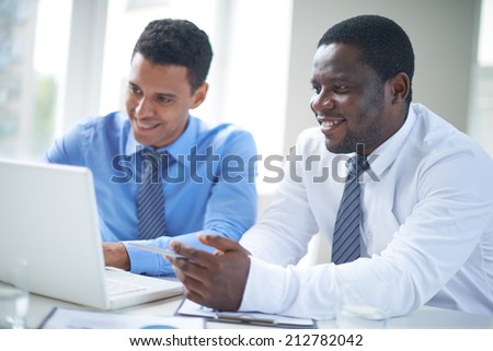 Businessman of African-american ethnicity pointing at laptop screen during presentation