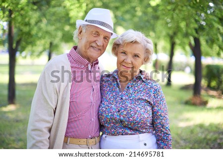 Couple of senior man and woman looking at camera in the park at summer