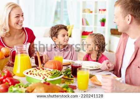 Portrait of happy family of four sitting at festive table and communicating