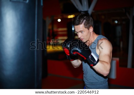 Male boxer in boxing gloves training in sports gym