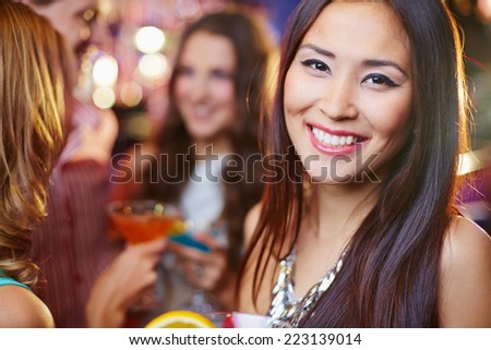 Joyful Asian girl at a party, her friends in the background